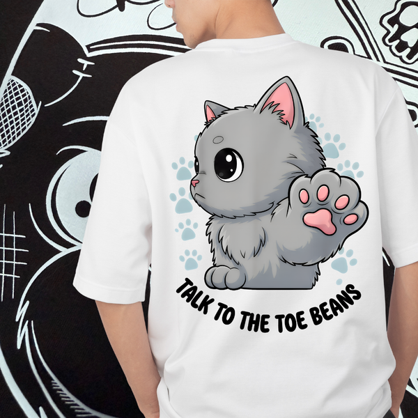 Person wearing a white t-shirt with a cartoon cat and text design talk to the toe beans on the back.