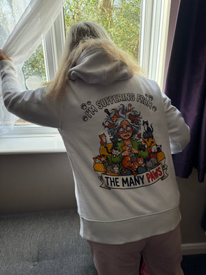 person looking out of window wearing a white hoodie with a tattoo style design of a woman with lots of cats