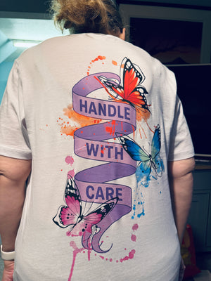 Person wearing a t-shirt with butterfly design and 'Handle with Care' text.