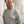 Person wearing a gray sweatshirt with text and graphics, standing indoors.