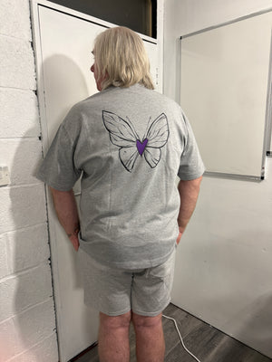 Person wearing a gray sweatshirt with a butterfly design on a white surface.