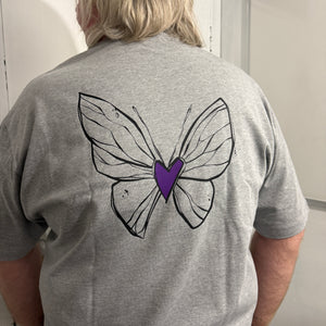 Person wearing a gray hoodie with a butterfly design on the back, standing in a room.