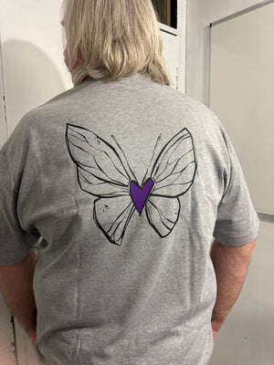 Person wearing a gray hoodie with a butterfly design on the back, standing in a room.