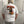 Person wearing a white t-shirt with a graphic design of a bear and hug dealer text, standing in an indoor setting.