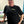 Person wearing a black t-shirt with a colorful cartoon frog graphic design and text in an indoor setting