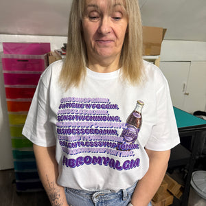 Person wearing a white t-shirt with purple text and graphics concerning fibromyalgia, standing indoors.