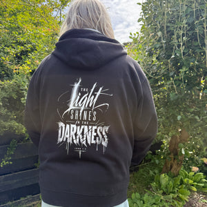 Person wearing a black hoodie with white text outdoors