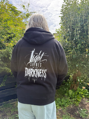 Person wearing a black hoodie with white text outdoors