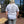 Person wearing a white t-shirt with text and graphics outdoors on a clear day.