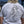 Person wearing a white t-shirt with a graphic design and text on the back.