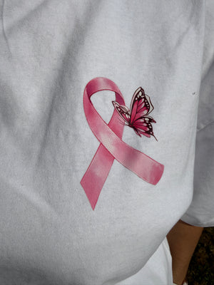 A close-up of a white fabric surface featuring a pink awareness ribbon and butterfly graphic printed on it.
