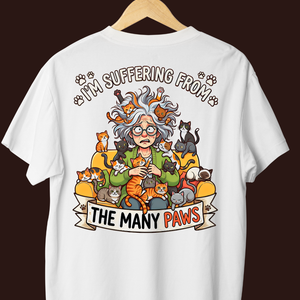 White t-shirt with a cartoon design of a person surrounded by cats and text on a dark background