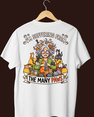 White t-shirt with a cartoon design of a person surrounded by cats and text on a dark background