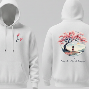 White hoodie with cherry blossom design and the text Live in the moment on front and back on a gray background