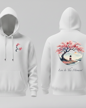 White hoodie with cherry blossom design and the text Live in the moment on front and back on a gray background