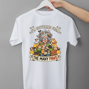 White t-shirt with cartoon design and text 'I'm suffering from the many paws' on a gray background
