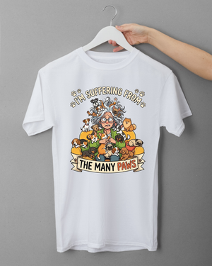 White t-shirt with cartoon design and text 'I'm suffering from the many paws' on a gray background