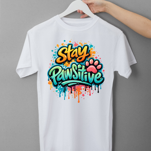 White t-shirt with 'Stay Pawsitive' design on a hanger against a gray background